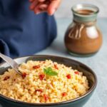 Vibrant bowls of fluffy couscous topped with roasted vegetables, herbs, and lemon wedges