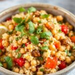 Colorful bowl of Vegan Couscous with roasted vegetables, herbs, and lemon wedges.
